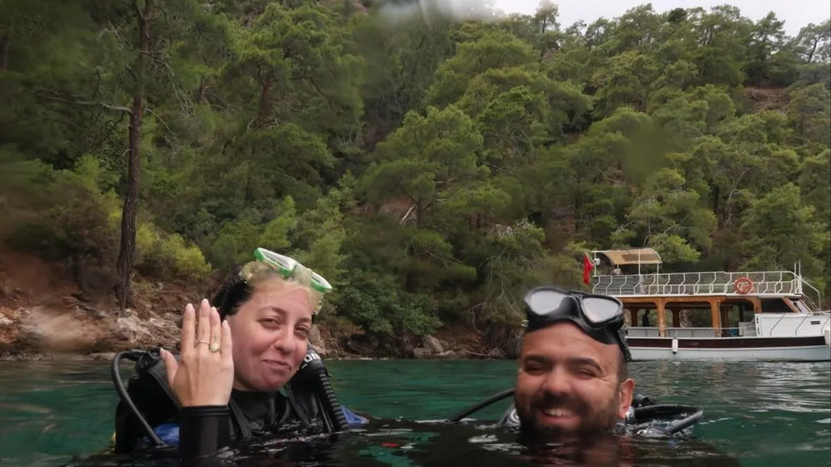 Fethiye'de dalış sonrası denizde yüzen çift, yüzük takılı eliyle poz veriyor